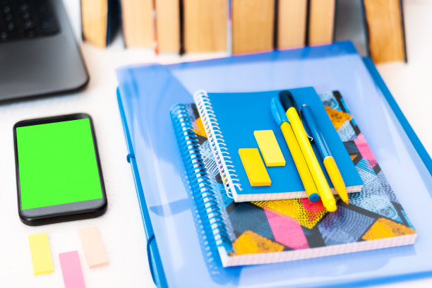 在家工作，绿屏手机，书籍和笔记本。教育背景，大流行期间在家工作。居家隔离的概念图片下载