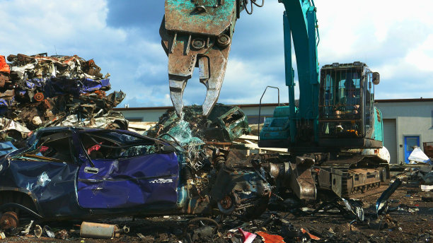 在垃圾场忙了一天。机械爪拆旧汽车图片下载