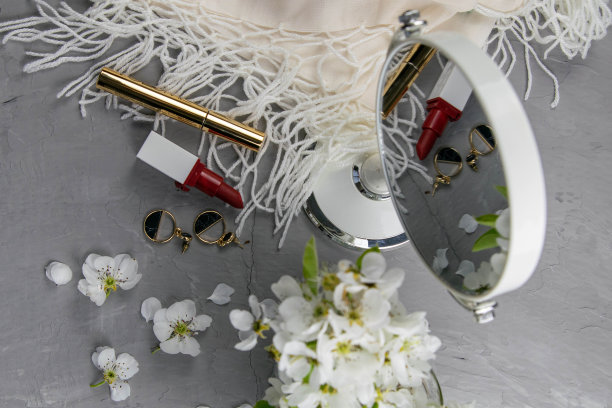 化妆品放在灰色的梳妆台上。前视图,特写镜头。镜子，阴影，口红和白花图片下载