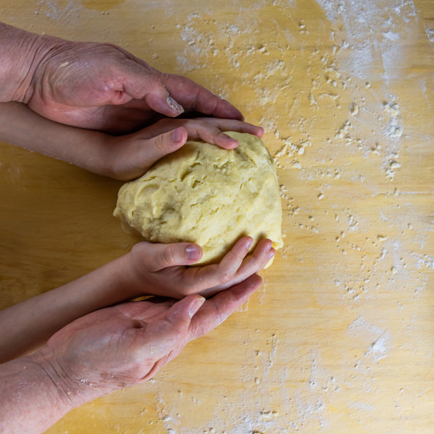一个祖母和一个孩子的手一起握着一个面团图片下载
