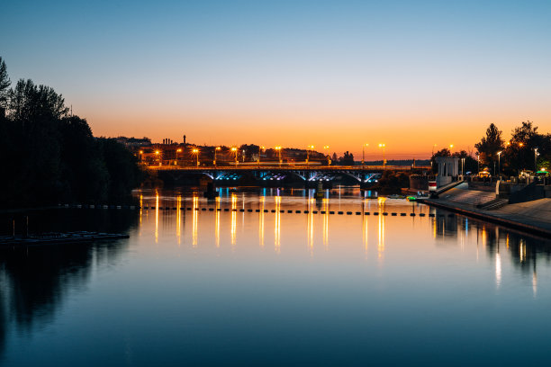 河的背景傍晚的城市。从码头上看到的城市全景。河上有座公路桥。图片下载