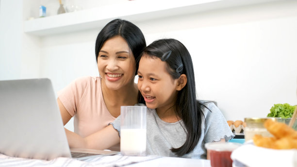 母亲和女儿在厨房与祖父母进行视频通话，家庭欢乐时光，使用笔记本电脑进行视频会议，疫情期间的隔离活动，在线学习概念图片下载