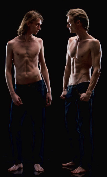 白人兄弟穿着牛仔裤站在黑色背景前图片下载