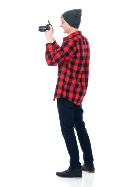 白人男性游客戴着针织帽，手持相机站在白色背景前图片下载