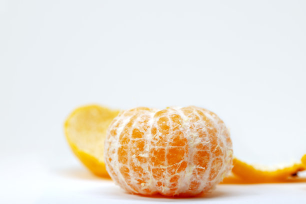 白色背景下的鲜橘子剥皮。柑橘类水果摄影棚照片。整个没有皮的橘子。图片下载