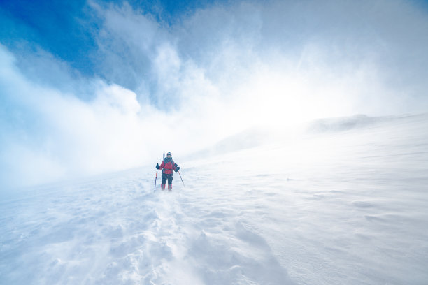 在暴风雪中，年长的登山者在高海拔山峰上向下移动素材图片