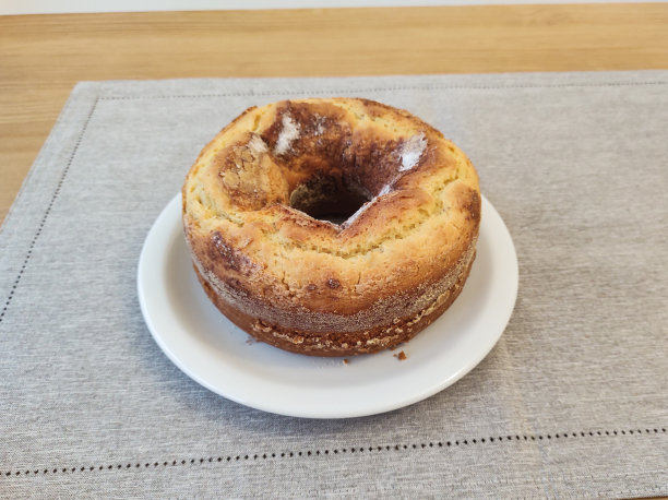 圆形玉米粉蛋糕放在白色盘子上，从上面看，背景模糊。图片下载