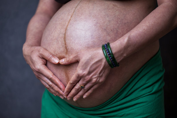 妊娠晚期孕妇的腹部，她的手盖住心脏形状的胎儿图片下载