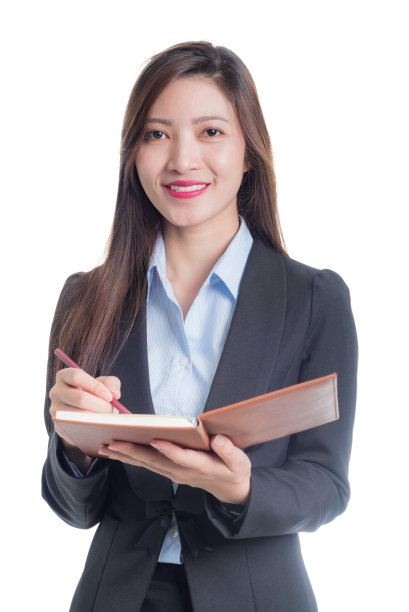 一位女商人面带微笑，手里拿着一支铅笔和一本棕色的笔记本。图片下载