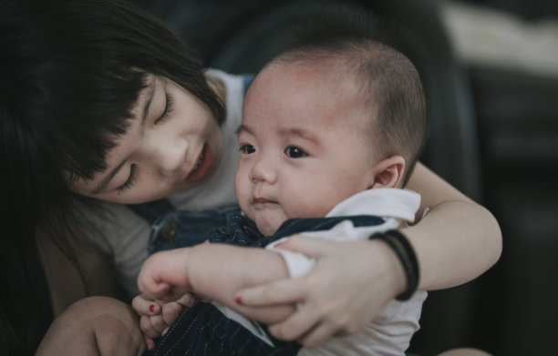 一个亚裔中国小妹妹照顾着，说话，抱着她正在哭的小弟弟图片下载