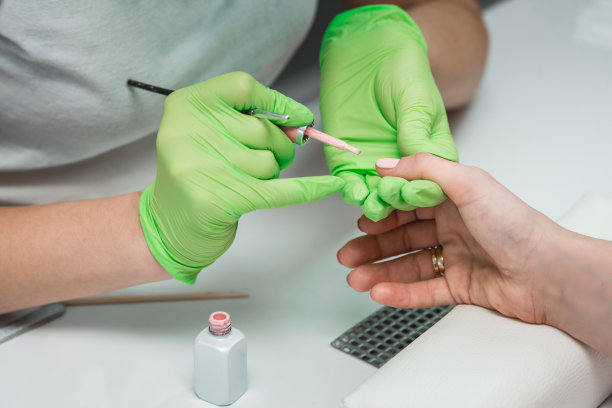 专业的美甲大师在绿手套制作美甲沙龙图片下载