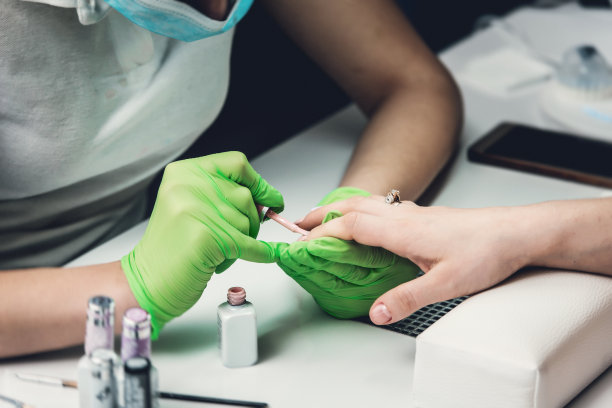 专业的美甲大师在绿手套制作美甲沙龙图片下载