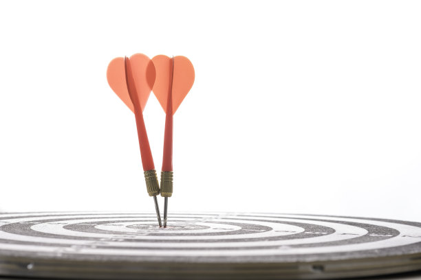 两个红色飞镖击中中心的目标板上的蓝色散焦背景。企业投资目标和目标概念。图片下载