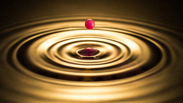 美丽的红色水滴落在金色的水中图片下载