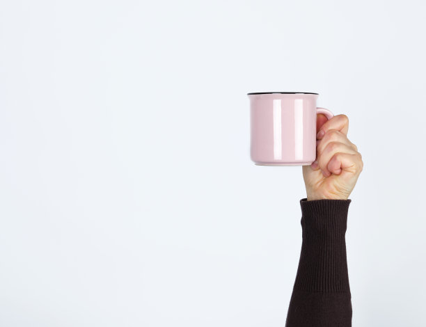 白色背景上女性手握粉红色陶瓷杯图片下载
