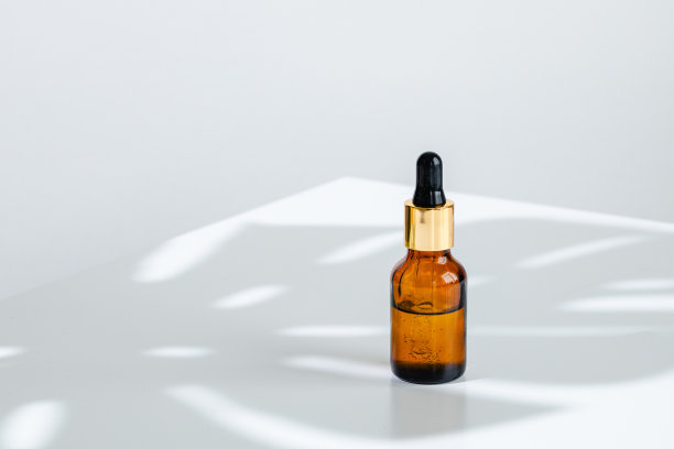 化妆瓶与移液管在白色背景与热带花卉阴影的创意照片图片下载