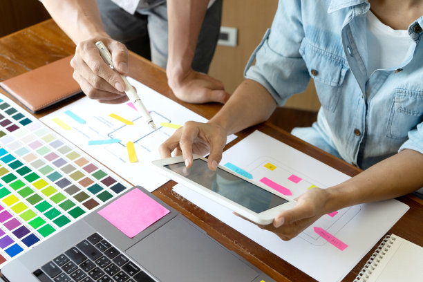 一群年轻的设计师在办公室工作，设计了一款新产品，使用颜色表和电脑笔记本电脑为新的智能手机设计概念图片下载