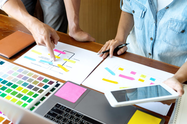 一群年轻的设计师在办公室工作，设计了一款新产品，使用颜色表和电脑笔记本电脑为新的智能手机设计概念图片下载