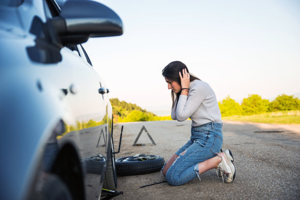 绝望的年轻女子试图用轮胎撬换掉掉的轮胎素材图片