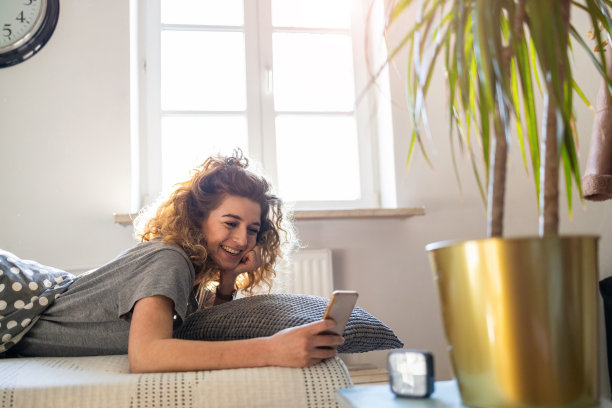 年轻女子在床上使用智能手机图片下载