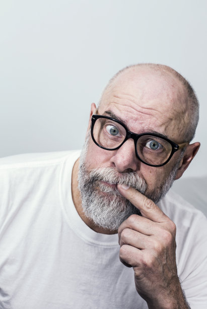 一个手指放在嘴唇上的秃顶成年男子图片下载