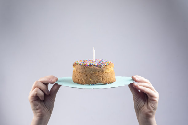 双手拿着一个香草蛋糕在白色的背景图片下载