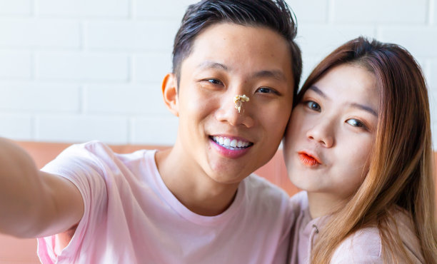 情侣们用智能手机自拍，男友脸上沾着蛋糕污渍图片下载