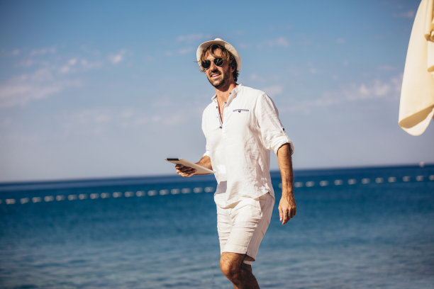 男人放松和使用平板电脑在海滩上图片下载