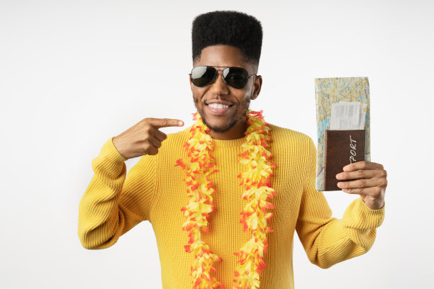 微笑的年轻非洲裔美国人拿着护照和票，指着孤立的白人背景图片下载