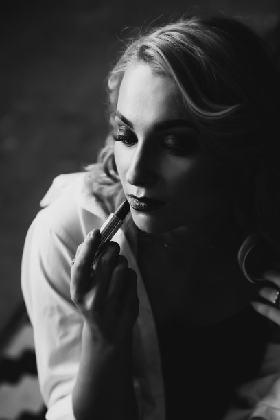 一个手里涂着口红的漂亮女人的肖像。黑白艺术照片。软选择聚焦。图片下载