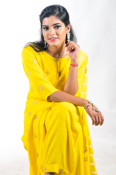 年轻女子在一个流动的黄色churidhar微笑着向前看图片下载