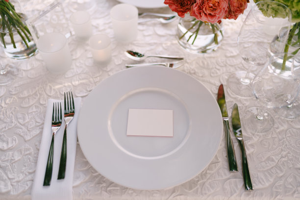 婚礼晚宴招待会。从上面看白色的圆形盘子特写。粉红色、橙色、绿色的花束。粉色的玫瑰，橙色的小玫瑰。俯视图图片下载