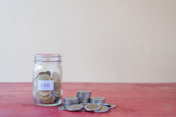 把硬币放在玻璃杯里，放在红色的木桌上。工作场所与复制空间-投资，商业，金融和银行概念图片下载