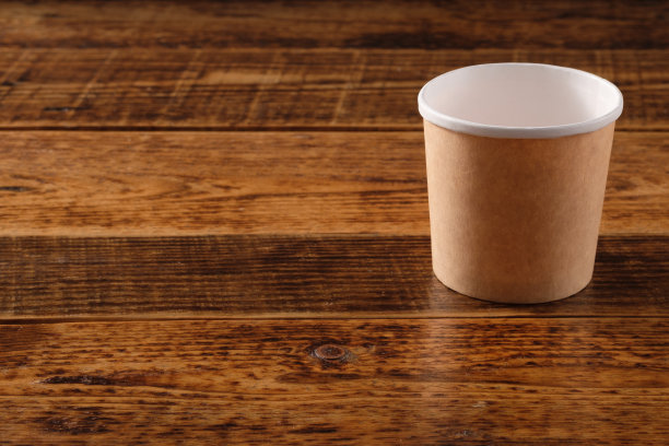 大的棕色纸杯孤立在木制背景上。环保的一次性食品包装。保护自然和循环利用的理念。副本的空间。图片下载