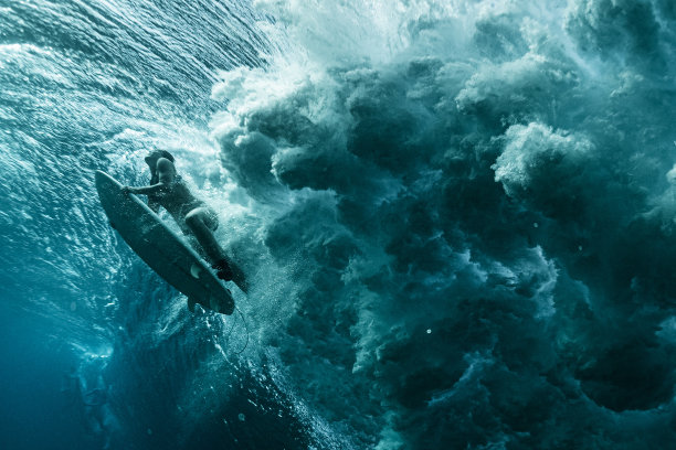 水下女子冲浪者通过强大的海浪图片下载