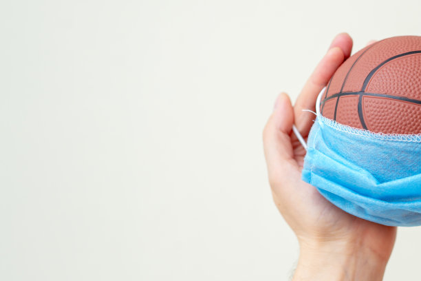 男人手里拿着医用面具的篮球。图片下载
