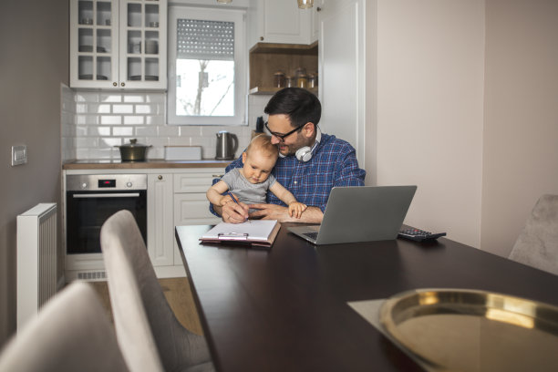年轻的父亲远程工作，照顾他的儿子。图片下载