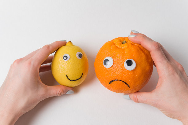 手握着柠檬和橙子，很有特色。食物与滑稽的脸在白色的背景图片下载