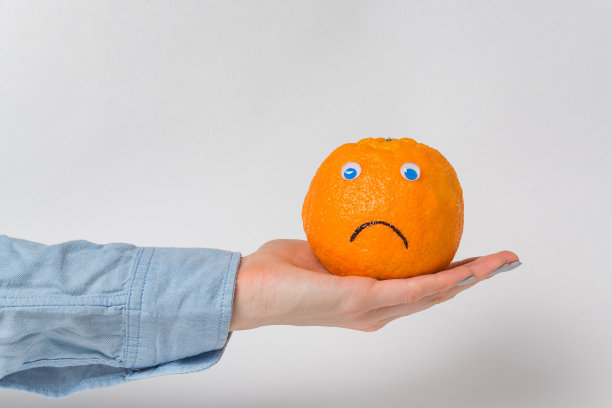 橙色的大眼睛和悲伤的微笑躺在掌心。白色背景。图片下载