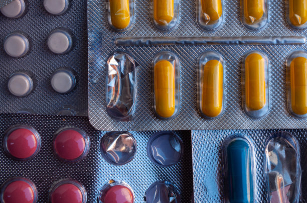 不同颜色的药片堆在半开的泡罩包装。背景图片图片下载