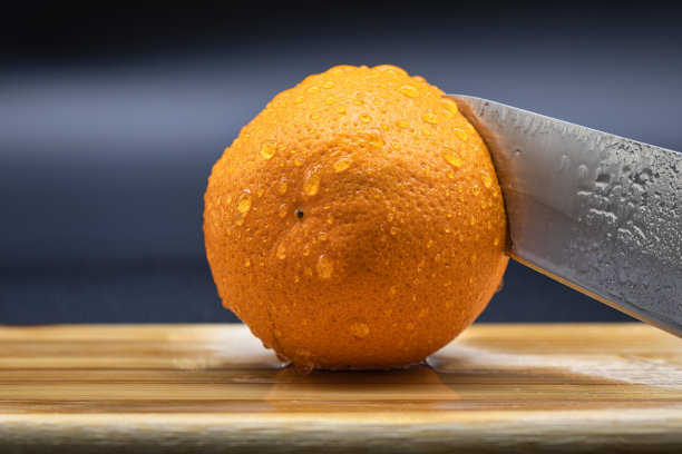 在木板上切橘子。鲜橙水果放在切菜板上做沙拉或榨汁。健康饮食、烹饪、节食的概念。靠近切片的橙子。图片下载