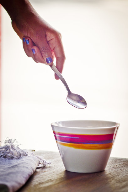 五颜六色的杯子和勺子由女孩的手拿着图片下载