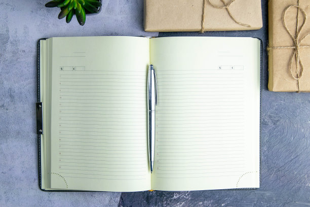 学校的笔记本与礼品在灰色的背景上，礼品盒与笔记本在桌子上。顶部视野与清晰的空间图片下载