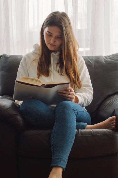 美丽的年轻女子正在家里看书。思考的女孩在读重要的书。图片下载
