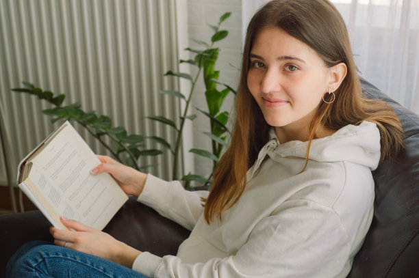 美丽的年轻女子正在家里看书。思考的女孩在读重要的书。图片下载