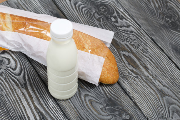 一瓶牛奶和包里的意大利脆皮面包。在刷过的松木板上。图片下载