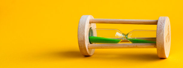 沙漏，里面有绿色的沙子，背景是黄色图片下载