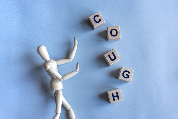 咳嗽单词立方体与一个木制的人在蓝色的背景图片下载