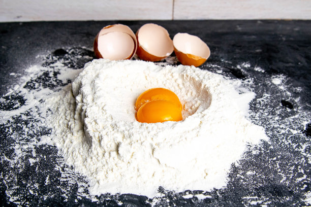 花岗岩厨房柜台上放着一堆面粉和蛋黄。前视图,特写图片下载