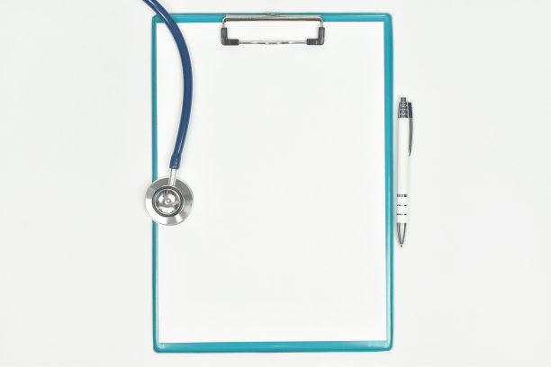医学模型与空白纸在剪贴板上，听诊器在医生的桌子上。图片下载